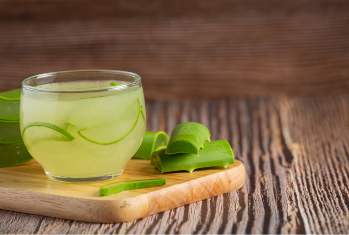 Aloe vera juice with leaves on a wooden table with numerous skin benefits.