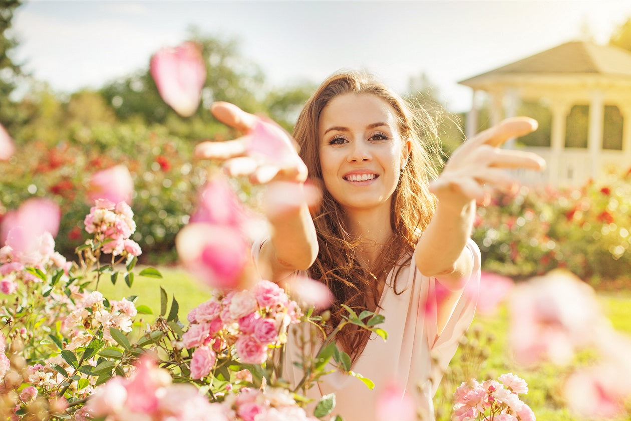  A woman surrounded by beautiful pink flowers in a garden, sharing 5 spring skincare tips.