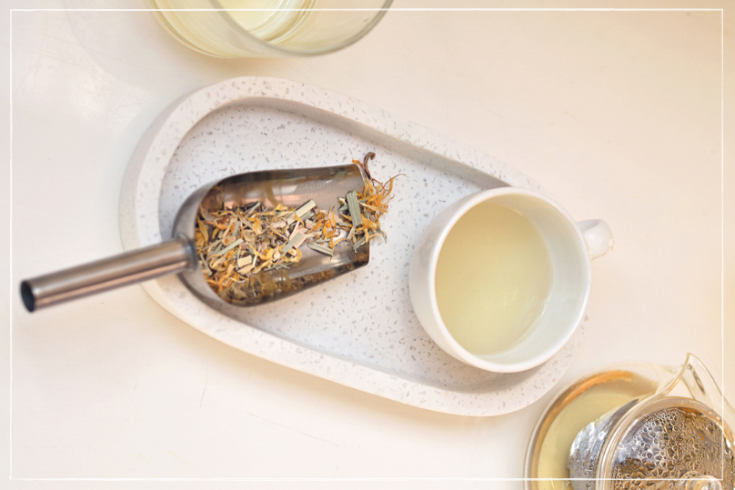A tray displaying a cup of herbal tea alongside a teapot filled with the same, signifying amazing benefits of herbal tea.