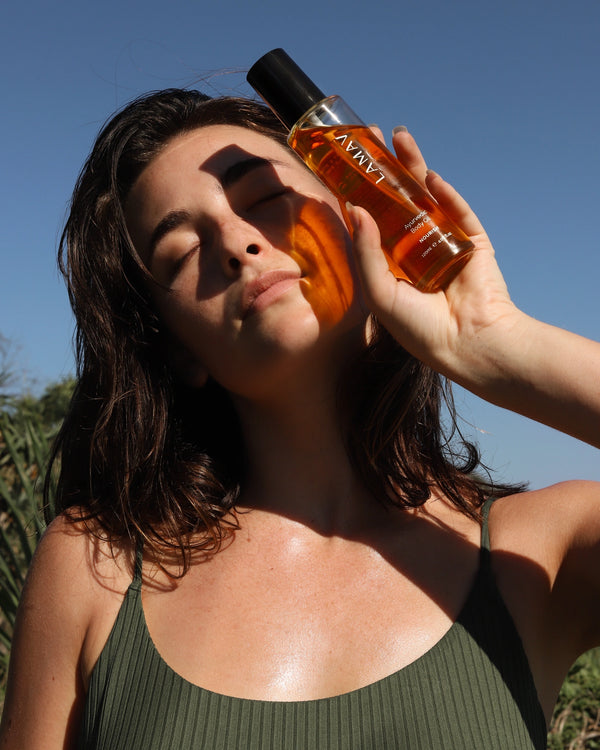 Ayurvedic Body Oil by LAMAV — woman holding the bottle casting a shadow on her face | Leaves skin soft and glowing