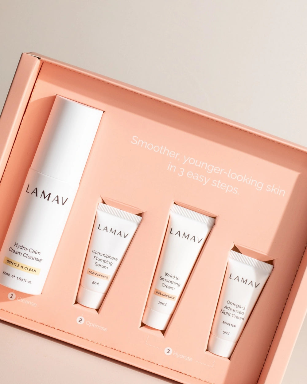 Age-Defence Pack by LAMAV — 4 skincare tubes on a wavy coaster next to pink box | Discover smoother, younger-looking skin