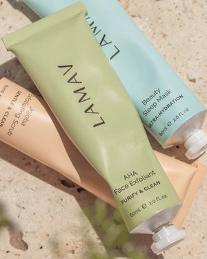 AHA Face Exfoliant by LAMAV — green tube lying flat with two other skincare tubes on stone | Gently exfoliate for a glow