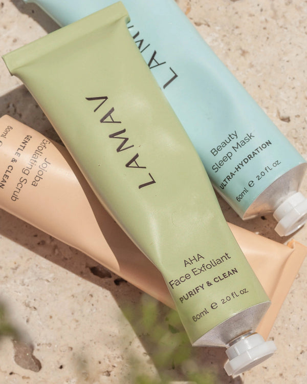AHA Face Exfoliant by LAMAV — green tube lying flat with two other skincare tubes on stone | Gently exfoliate for a glow