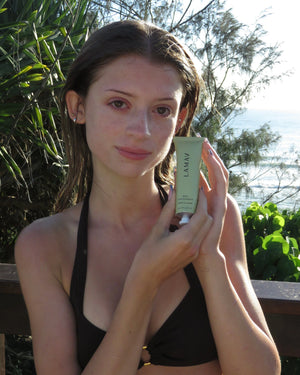 AHA Face Exfoliant by LAMAV — woman holding tube outdoors near the ocean | Achieve a smooth, clear summer glow