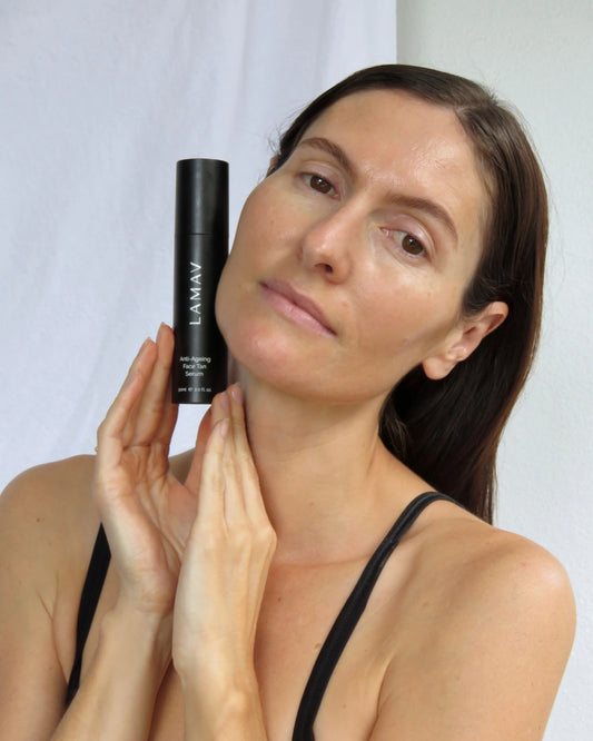 Anti-Ageing Face Tan Serum by LAMAV — woman holding the black bottle near her face | Develops a natural golden glow