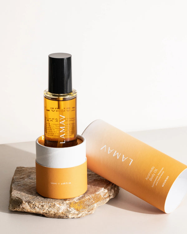 Ayurvedic Body Oil Nourish by LAMAV — bottle sitting inside its orange cylindrical packaging | Restores skin elasticity