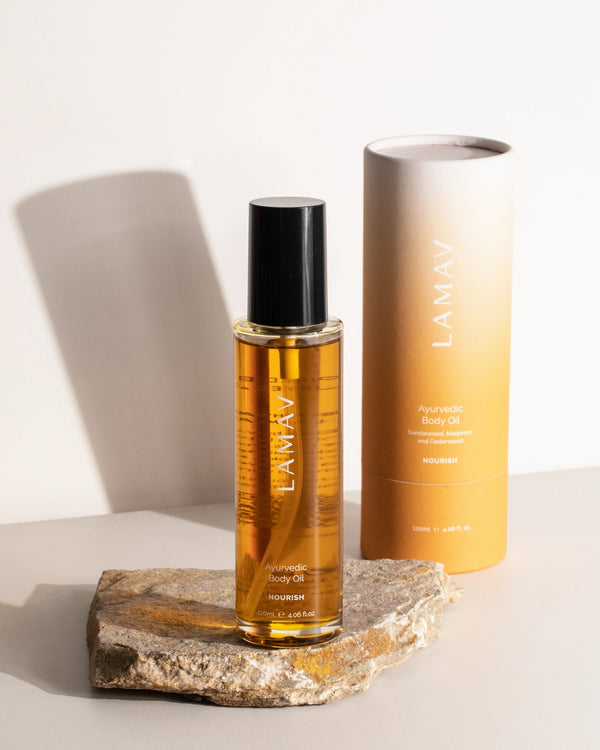 Ayurvedic Body Oil Nourish by LAMAV — bottle standing on a rock next to its packaging | Nourishing blend for dry skin