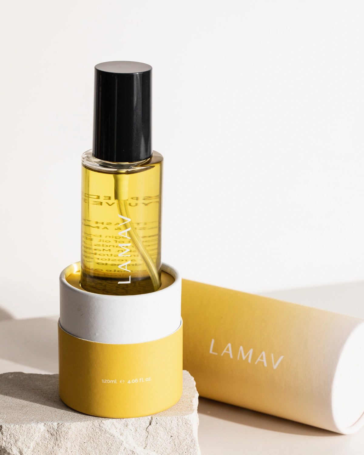 Ayurvedic Body Oil Unwind by LAMAV — bottle in yellow packaging resting on a stone | Calm the mind and body