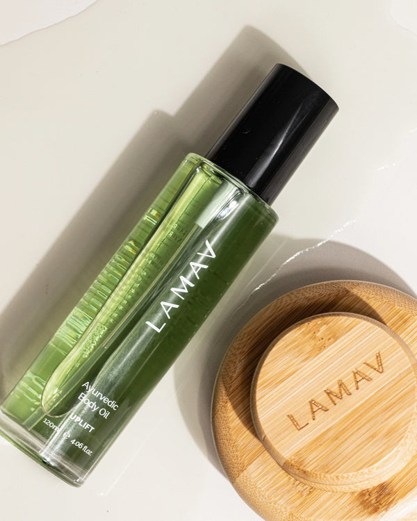 Ayurvedic Body Oil Uplift by LAMAV — green oil bottle lying next to a bamboo body brush | Enhances skin elasticity
