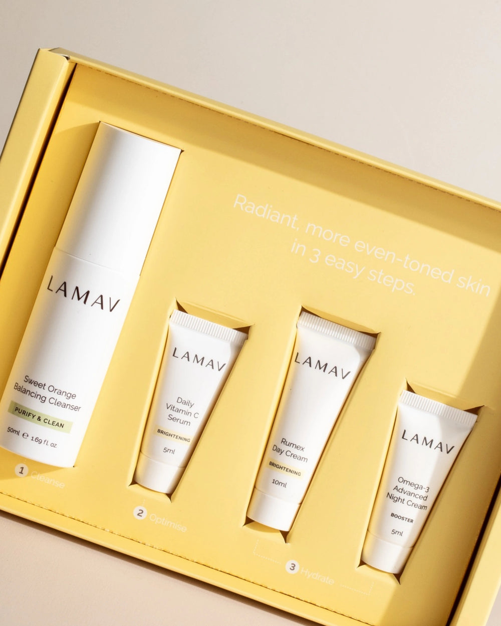Brightening Discovery Pack by LAMAV — closed box and four products on a wavy white stone | visibly reduces dark spots.