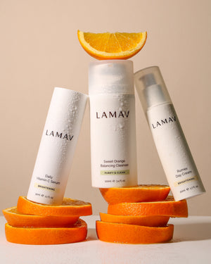 Brightening Essentials Set by LAMAV — skincare bottles resting on fresh bright orange slices | Vitamin C infused glow