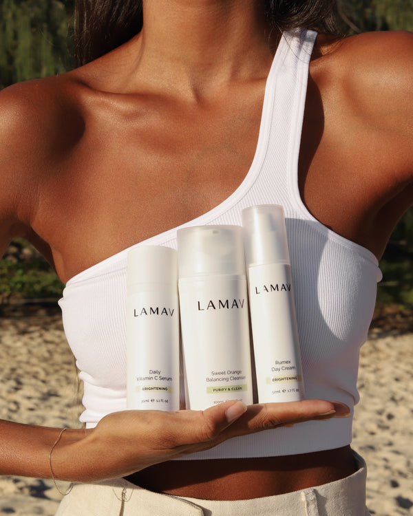 Brightening Essentials by LAMAV — woman holding three bottles in her hand outdoors | reveals a natural healthy glow
