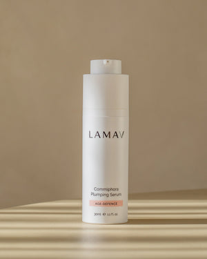 Commiphora Plumping Serum by LAMAV — white bottle standing in striped sunlight | Fights visible signs of aging