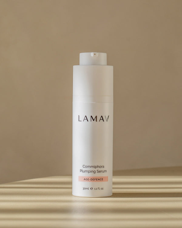 Commiphora Plumping Serum by LAMAV — white bottle standing in striped sunlight | Fights visible signs of aging