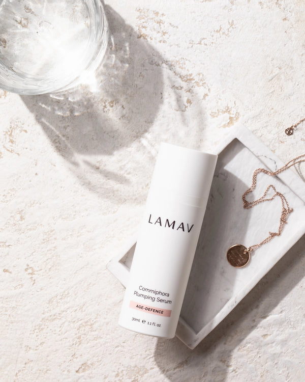 Commiphora Plumping Serum by LAMAV — bottle on a marble tray with a necklace | deeply hydrates and smooths fine lines