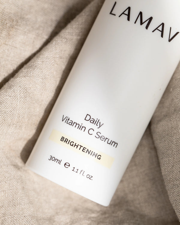 Daily Vitamin C Serum by LAMAV — close-up of white bottle on textured linen fabric | reduces pigmentation