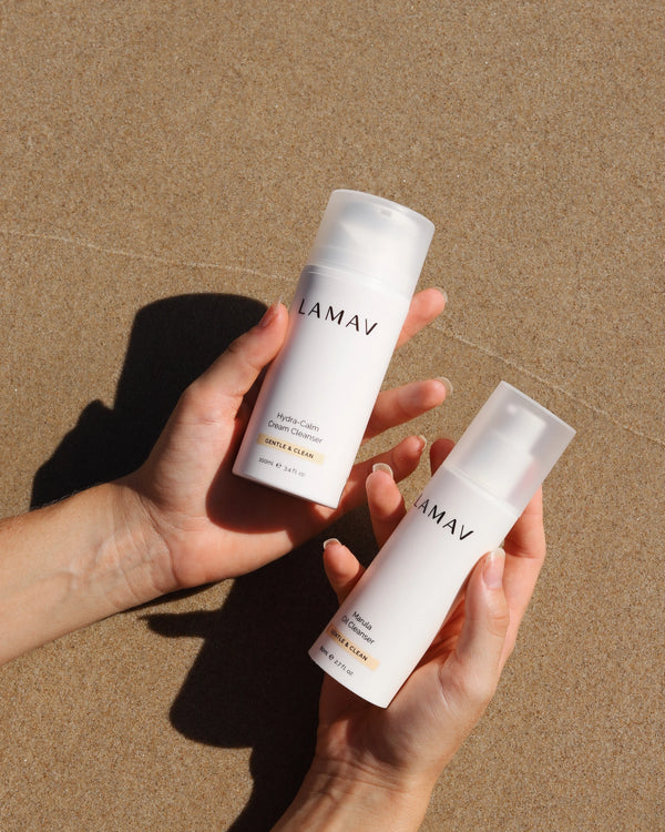 Double Cleansing Duo by LAMAV — hands holding the cleansers over warm sand in sunlight | Deeply cleanses and hydrates