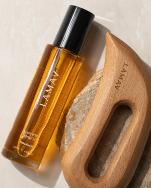 Full Body Bliss by LAMAV — oil bottle and wooden massager close up on natural stone | lymphatic drainage