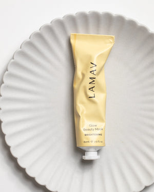 Glow Beauty Mask by LAMAV — yellow tube lying flat on a white ribbed ceramic plate | Reduces the appearance of pigmentation