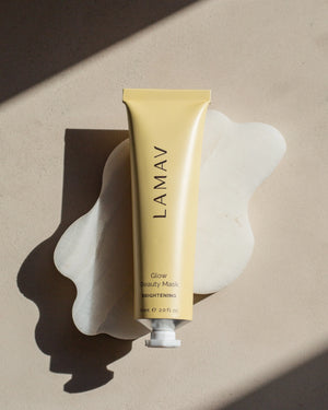 Glow Beauty Mask by LAMAV — yellow tube resting on a wavy white stone | Evens skin tone and boosts radiance