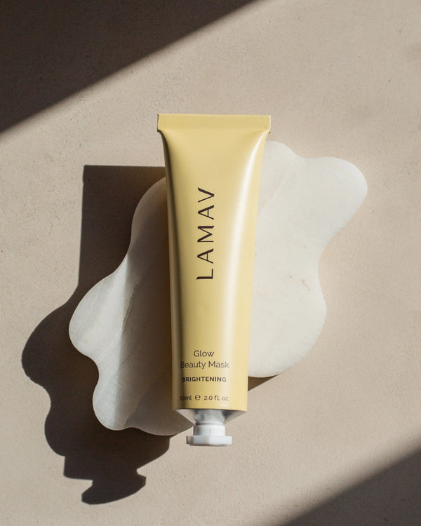 Glow Beauty Mask by LAMAV — yellow tube resting on a wavy white stone | Evens skin tone and boosts radiance