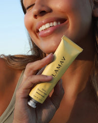 Glow Beauty Mask by LAMAV — smiling woman holding the yellow tube outdoors | Hydrates and revitalizes dull skin