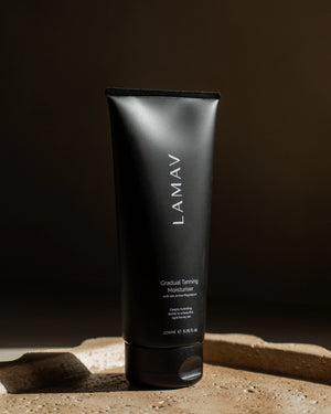 Gradual Tanning Moisturiser by LAMAV — black tube standing upright on a textured stone base | Develops a light honey tan
