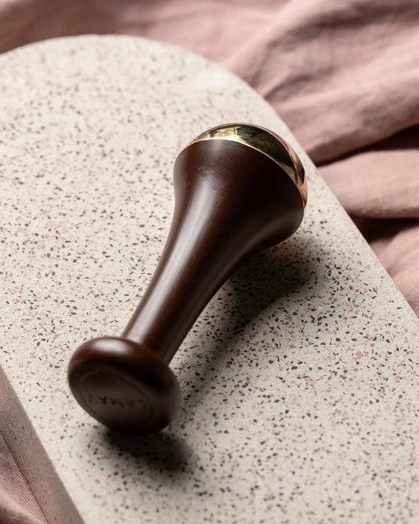 Ayurvedic Kansa Wand by LAMAV — wand resting on a speckled terrazzo stone | Relax facial muscles and tension