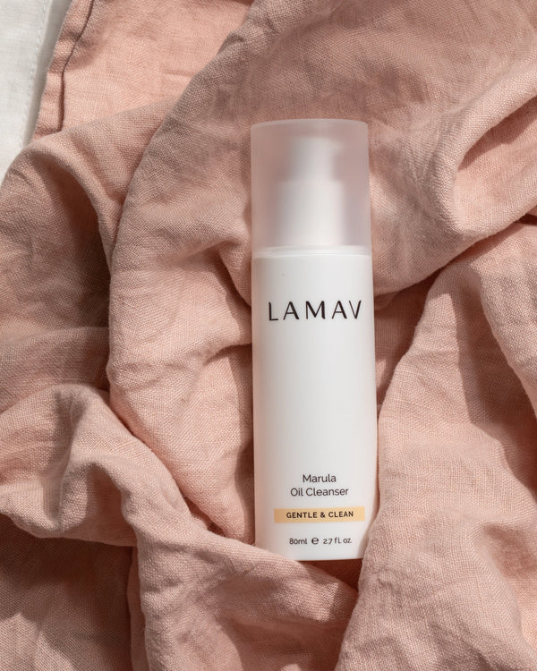 Marula Oil Cleanser by LAMAV — white bottle resting on pink textured linen | softens and purifies skin