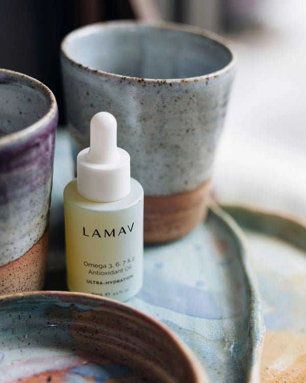 Omega 3, 6, 7 & 9 Antioxidant Oil by LAMAV — bottle next to ceramic cup | deep hydration