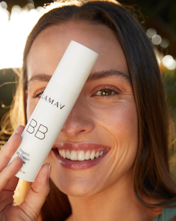Organic BB Cream by LAMAV — model smiling while holding bottle | natural radiant finish