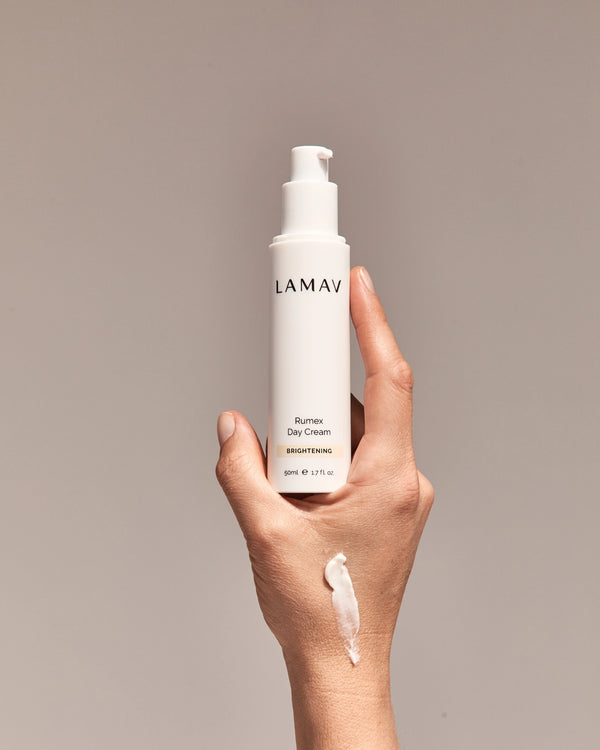 Rumex Advanced Lightening Cream by LAMAV — hand holding bottle with cream swatch | evens skin tone