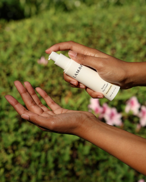 Rumex Advanced Lightening Cream by LAMAV — hands pumping cream outdoors | natural skin illumination