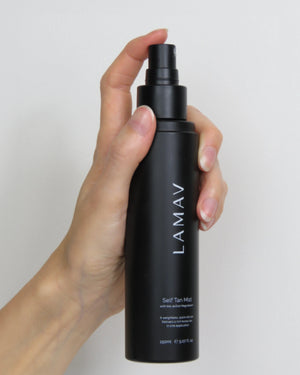 Self Tan Mist by LAMAV — hand holding the black mist bottle | glowing organic tan