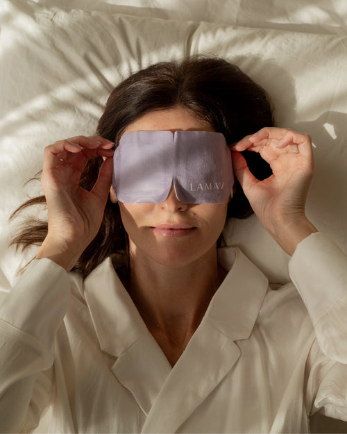 Self-Warming Eye Mask by LAMAV — woman lying down applying purple mask | relaxing sleep aid