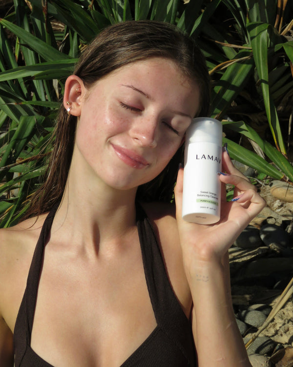 Sweet Orange Balancing Cleanser by LAMAV — model holding bottle with green plants | natural glow and purified skin