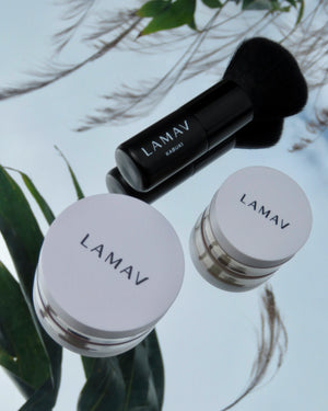 Teen Makeup Starter Kit by LAMAV — closed jars and brush resting on a mirror with green leaves | clean beauty essentials