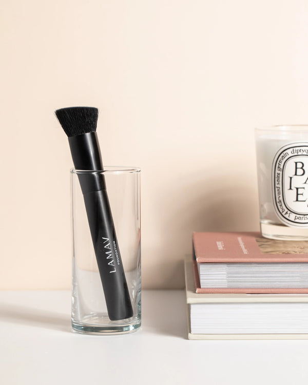 Vegan Foundation Brush by LAMAV — standing in a clear glass next to books | perfectly blends organic foundation