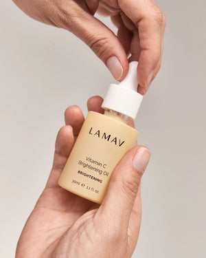Vitamin C Brightening Oil by LAMAV — close up of hands holding the yellow serum bottle | lightweight hydration