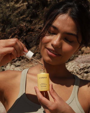 Vitamin C Brightening Oil by LAMAV — woman holding dropper outdoors in natural light | boosts skin radiance